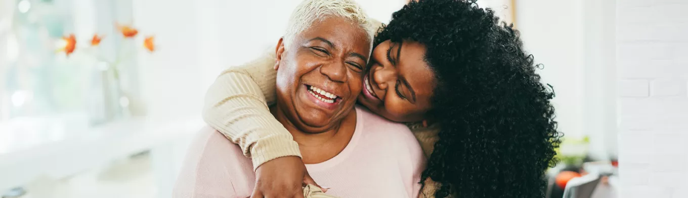 Old and young black women hugging and smiling 