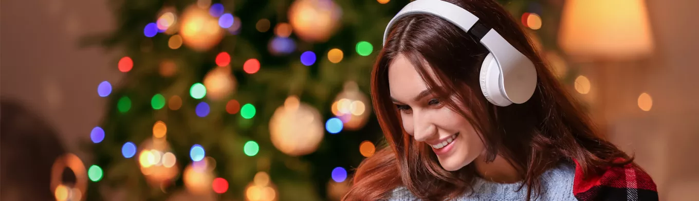 woman with headphones on with a Christmas tree in the background 