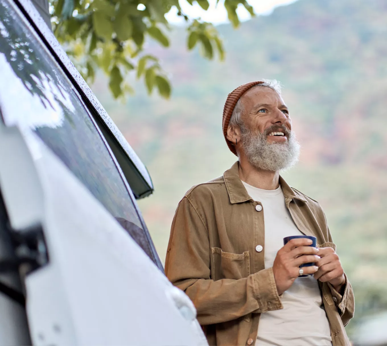 Happy old man leaning against his van out in nature