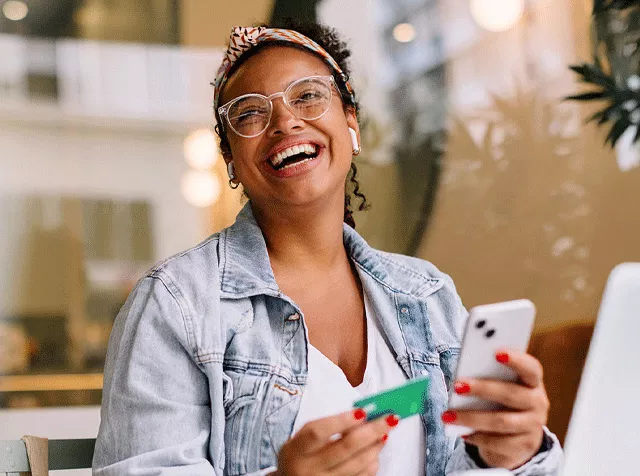 Lady holding a phone and a Pluxee Visa Card 