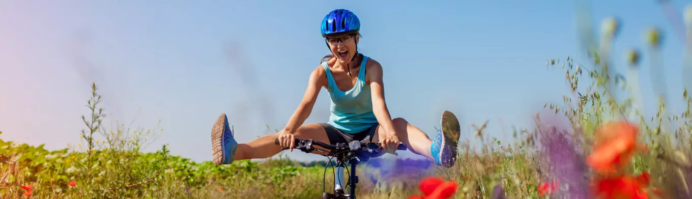 woman cycling through a meadow with he legs swinging out
