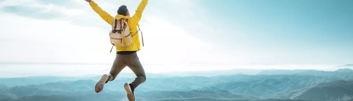 man on top of a mountain jumping in the air 