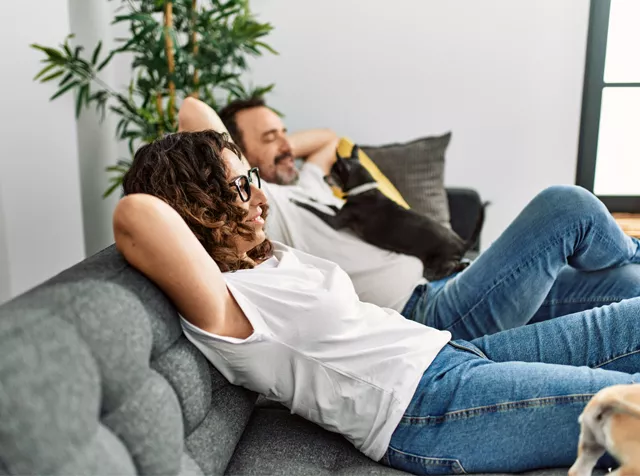 Man and woman relaxing on the sofa with a dog 