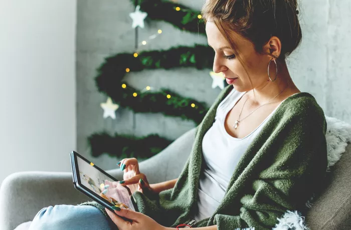 Christmas image of a woman sitting on her sofa with her iPad