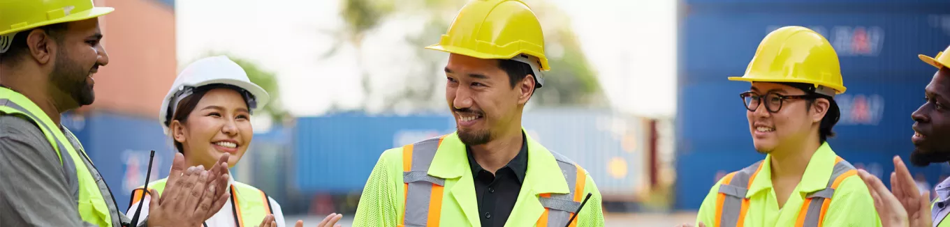 group of people on a construction site clapping their collgeaue 