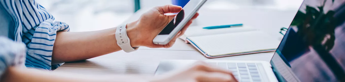 woman typing on phone and laptop 
