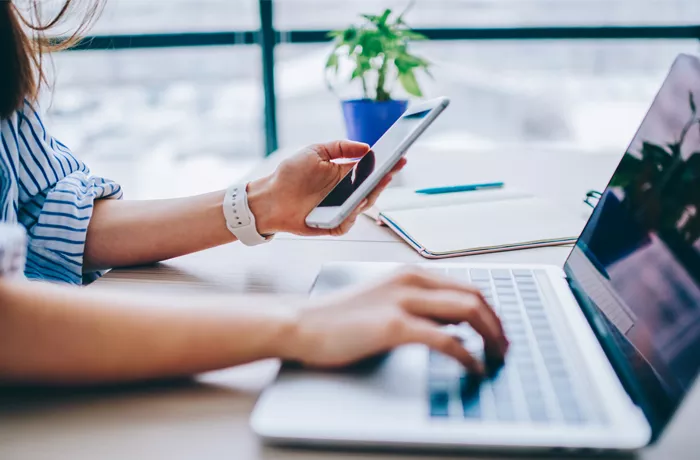 woman working on phone and laptop at the same time 