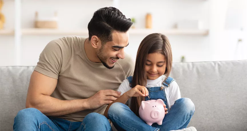 man with daughter saving some money in a piggy bank 