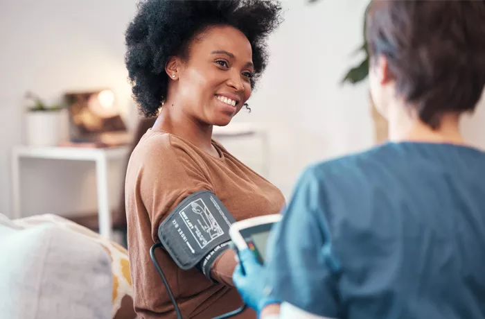 woman smiling as she takes a blood pressure test
