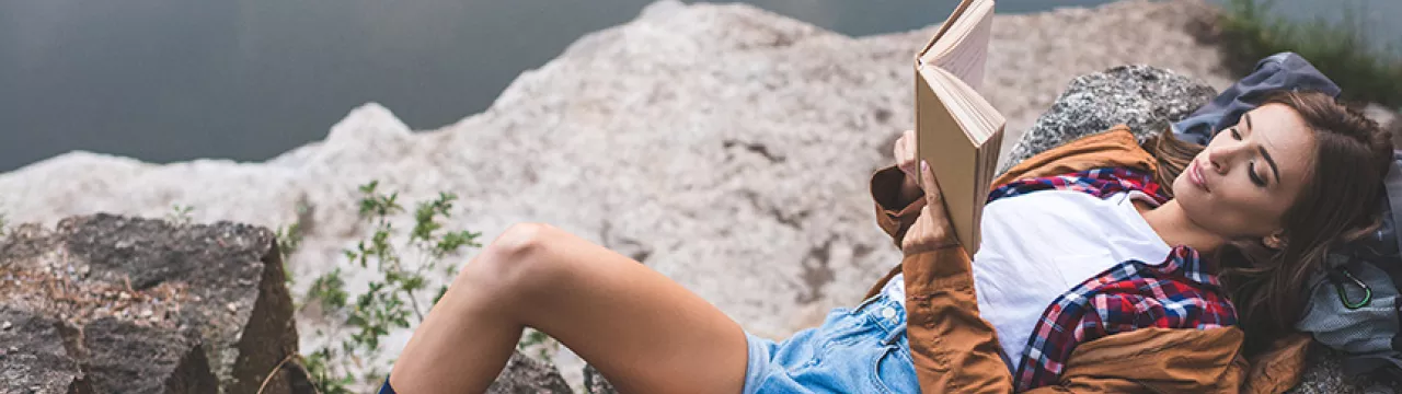 Lady relaxing on a rock with a book
