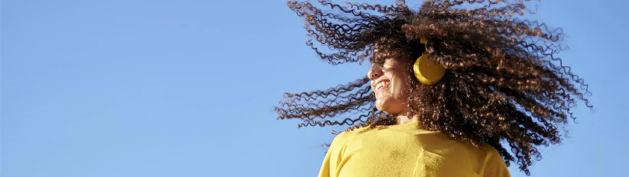 woman in a yellow jumper against a blue sky