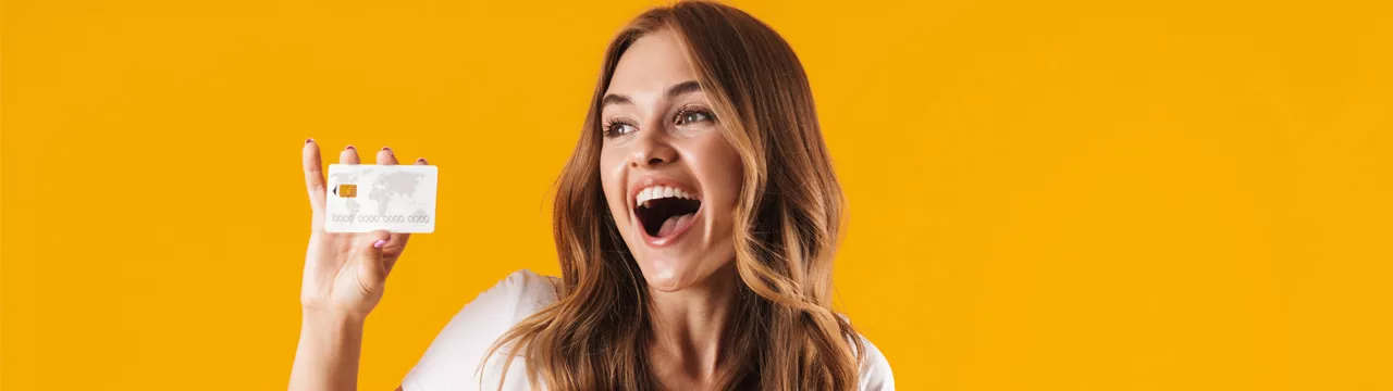 woman holding her credit card smiling on yellow background