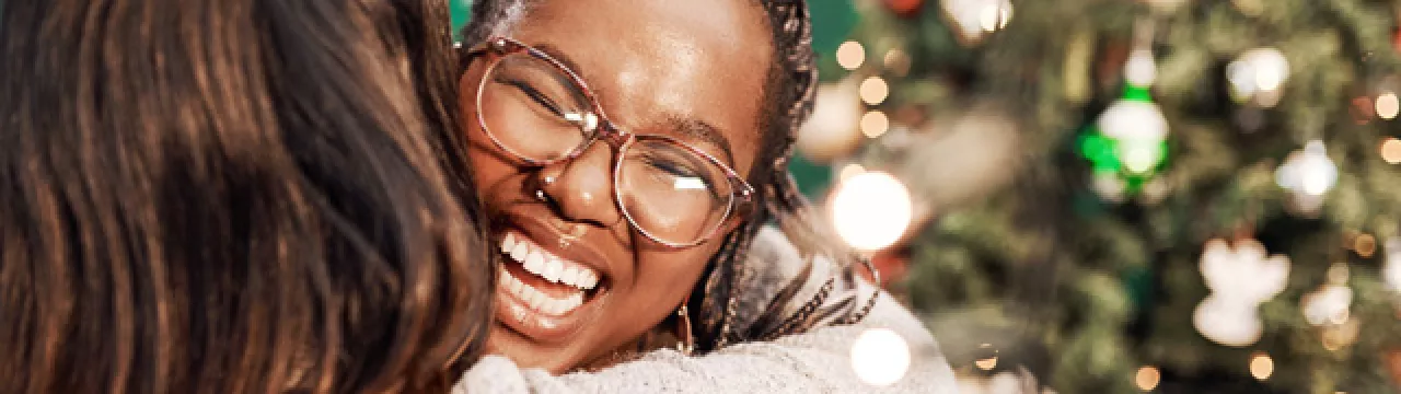 two women hugging by a Christmas tree