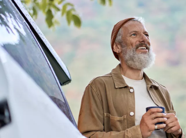 Man standing by his car out in nature