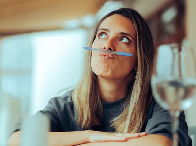 Lady thinking about what to do with a pen in her mouth