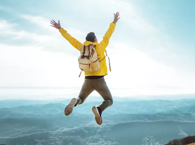 man jumping in the air on top of a mountain
