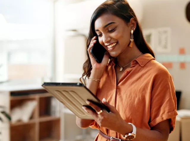 woman on phone and holding a tablet