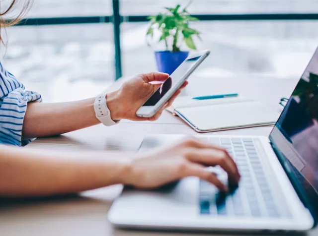 woman working on phone and laptop at the same time