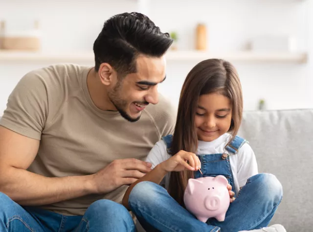 man with daughter saving some money in a piggy bank