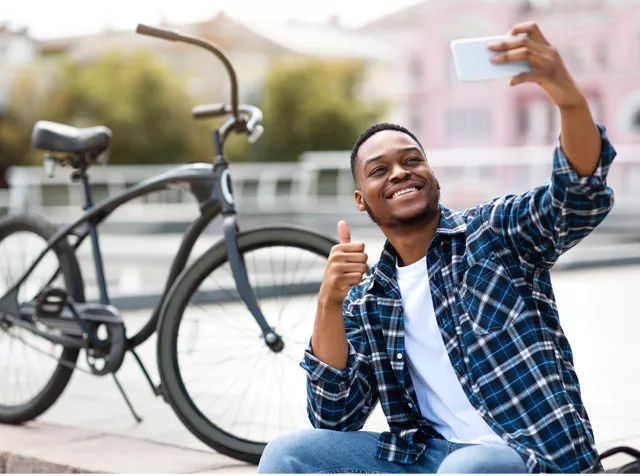 black man taking selfie with bike behind him