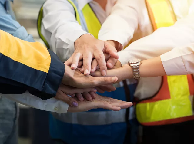 Team of factory workers with their hands in