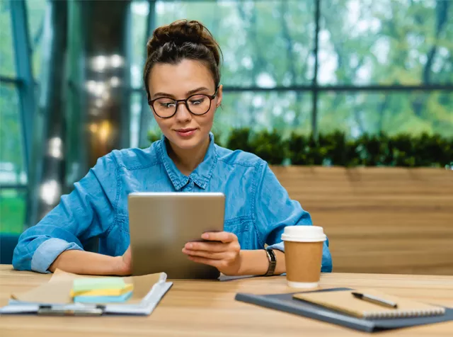 woman sitting at her desk with an ipad