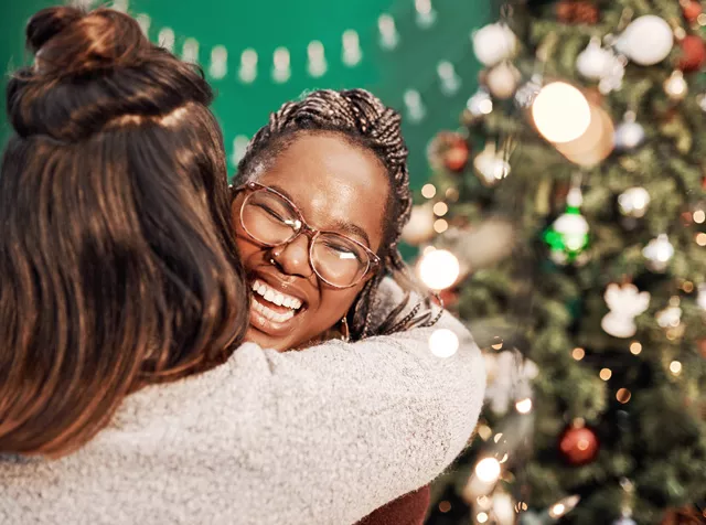 two women hugging by a Christmas tree