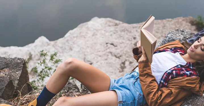 Lady relaxing on a rock with a book
