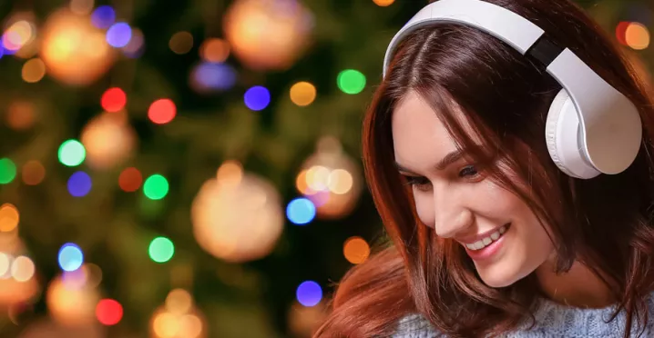 woman with headphones on with a Christmas tree in the background