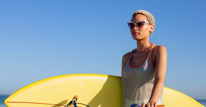 Woman carrying a yellow surfboard