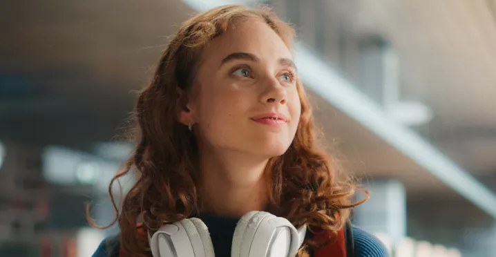 young woman looking happy with headphones around her neck