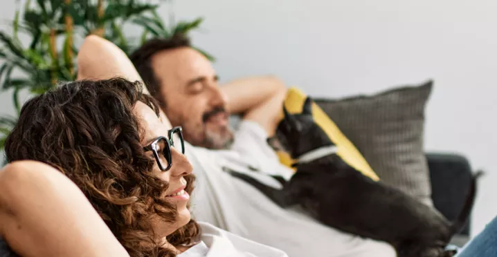 Man and woman relaxing on sofa with a dog
