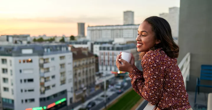 woman leaning over her balcony with a coffee