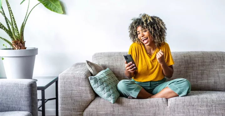 Woman on sofa looking at her phone and happy