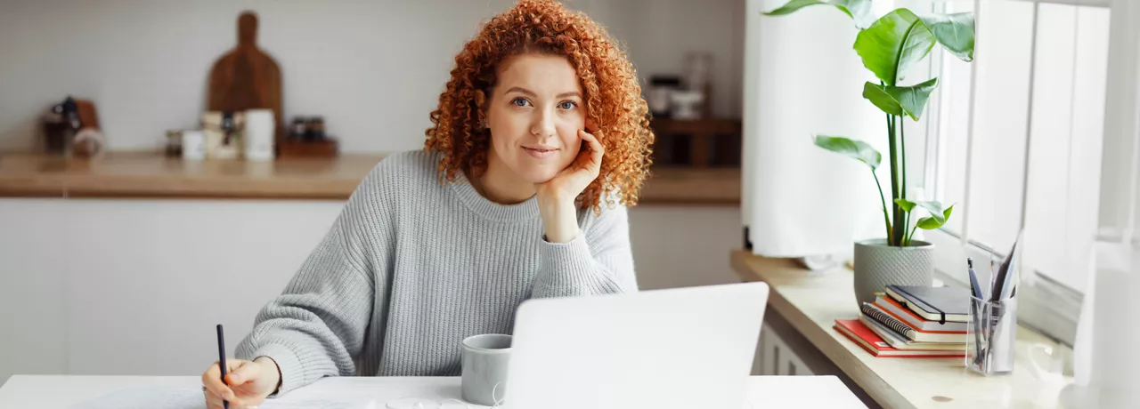 White woman with red curly hair on her laptop