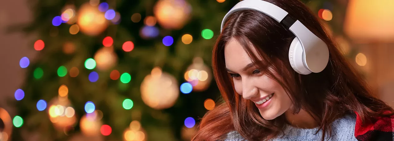 woman with headphones on with a Christmas tree in the background