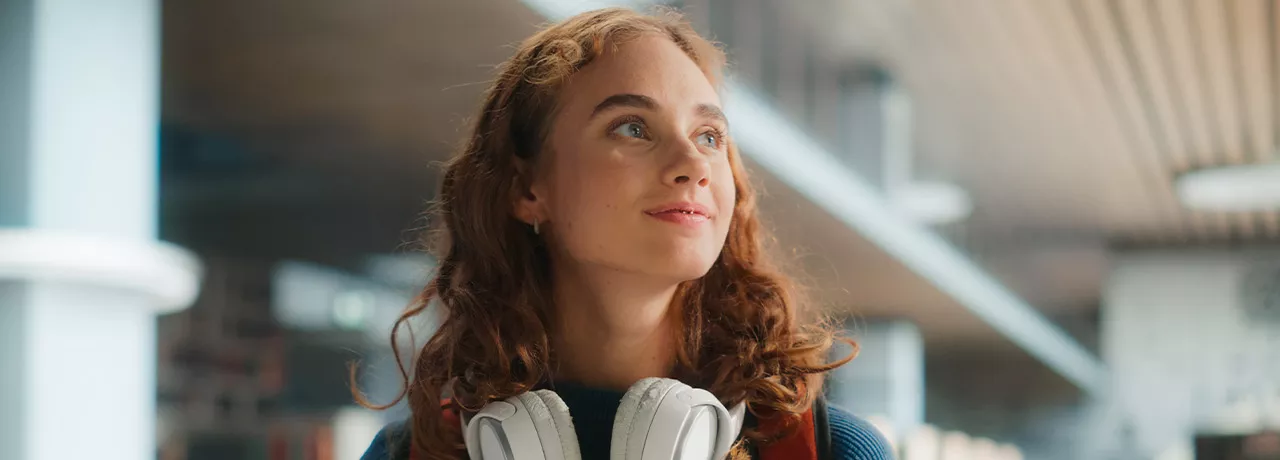 young woman looking happy with headphones around her neck