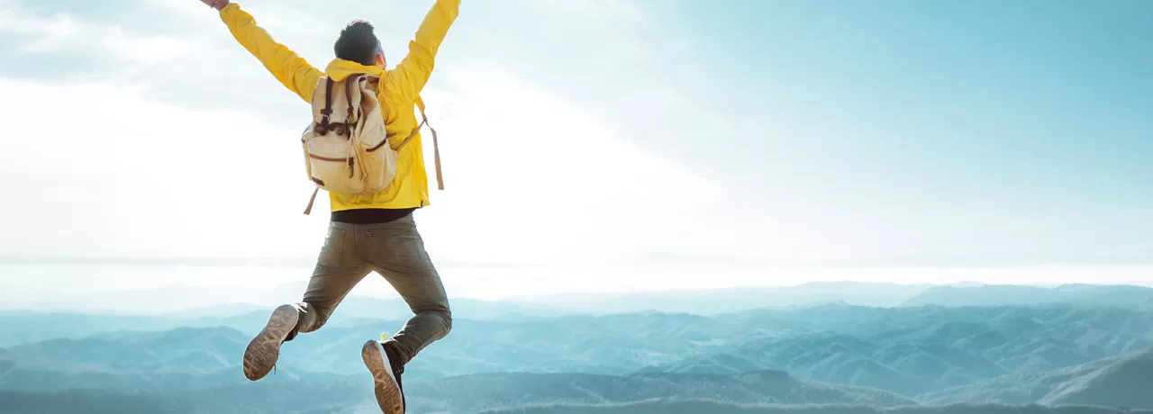 man on top of a mountain jumping in the air