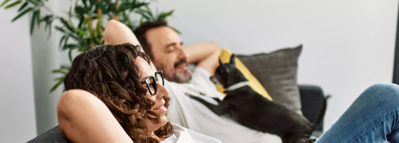 Man and woman relaxing on sofa with a dog