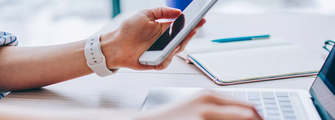 woman typing on phone and laptop