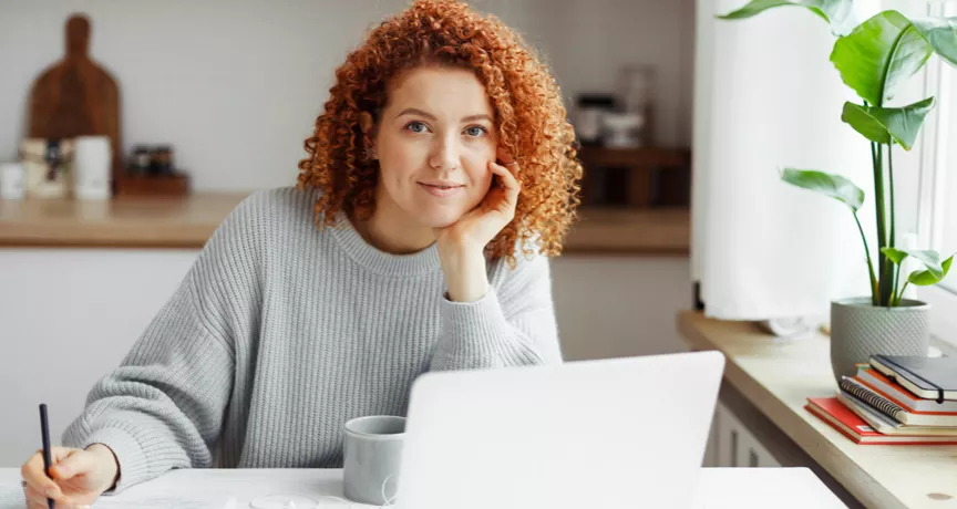 White woman with red curly hair on her laptop