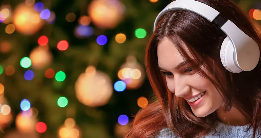 woman with headphones on with a Christmas tree in the background