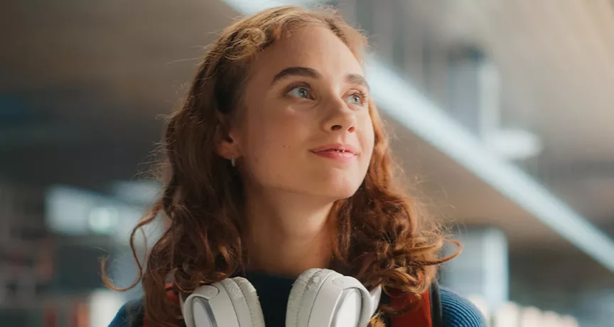 young woman looking happy with headphones around her neck
