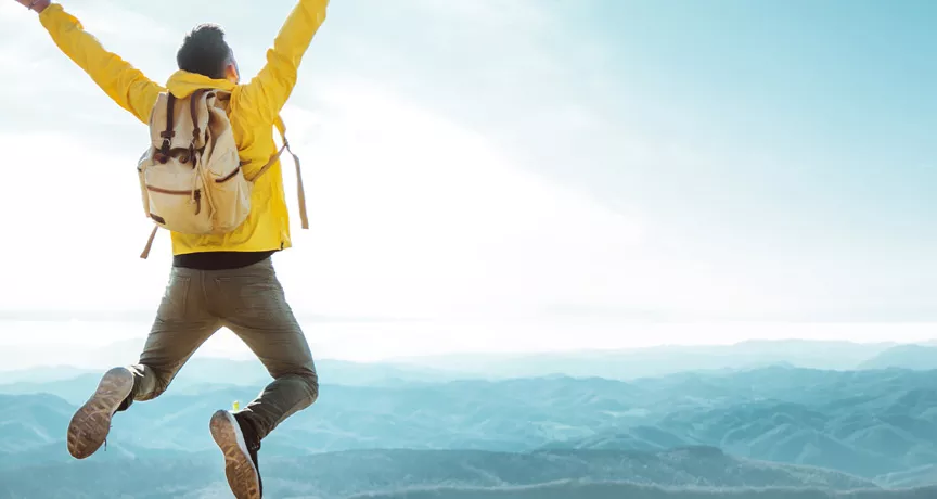 man on top of a mountain jumping in the air