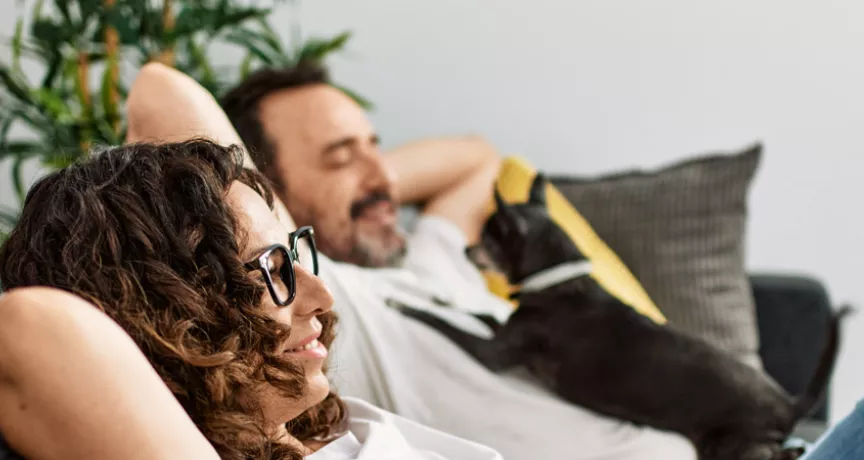 Man and woman relaxing on sofa with a dog