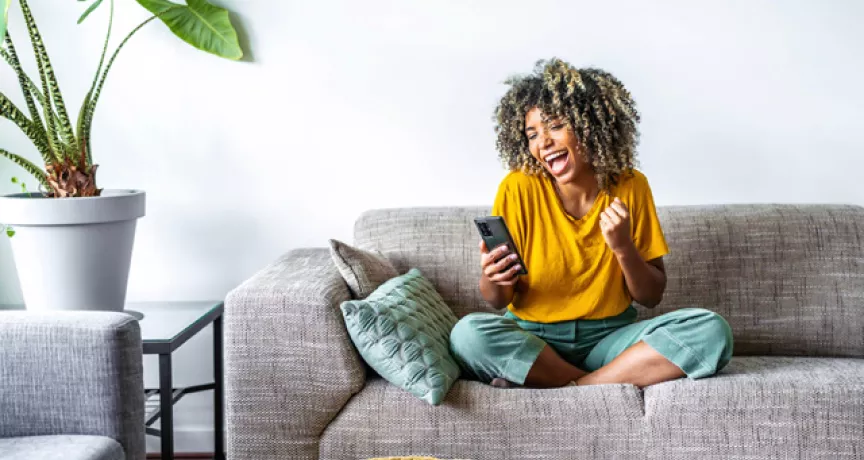 Woman on sofa looking at her phone and happy