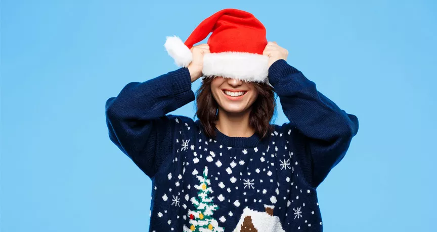 woman wearing an Xmas jumper pulling hat over head
