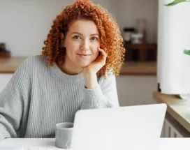 White woman with red curly hair on her laptop
