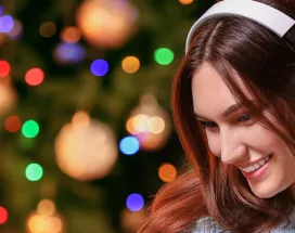 woman with headphones on with a Christmas tree in the background