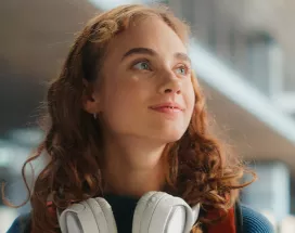 young woman looking happy with headphones around her neck